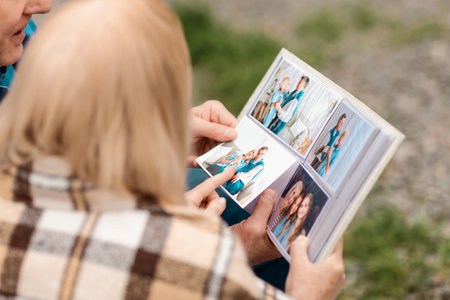 Sharing happy memories. Senior man with his wife leafing through photo album outdoorsの写真素材
