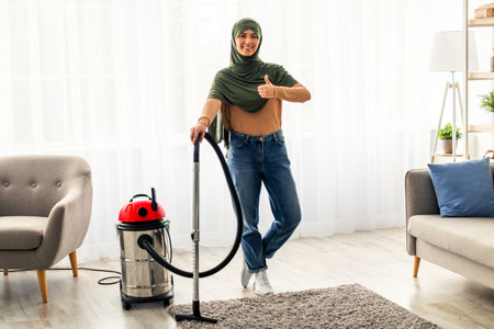 Young woman enjoying cleaning at home while using a vacuum cleanerの写真素材