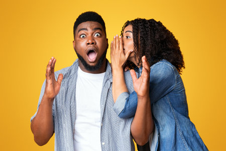 A man reacts in surprise to a womans secret on a yellow backgroundの写真素材