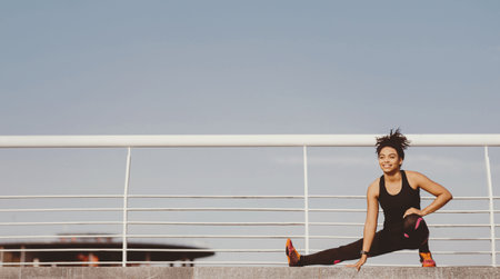 Gymnastics, pilates and fitness outdoors. African american girl in sportswear doing warm-upの写真素材