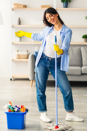Young woman enjoys cleaning her home while listening to musicの写真素材