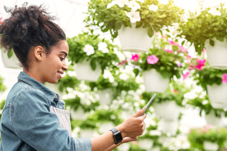 African american girl in denim shirt with smart watch typing at smartphone for eco blogの写真素材