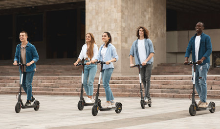 Five friends having pleasant ride on motorized kick scootersの写真素材