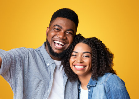 A joyful couple shares a cheerful moment against a bright yellow backgroundの写真素材