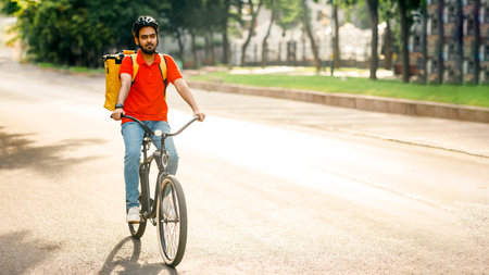 Modern delivery in city. Young man in helmet with bag rides on bicycleの写真素材