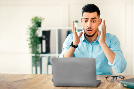 Young Arab businessman reacting to unexpected news while working in the office