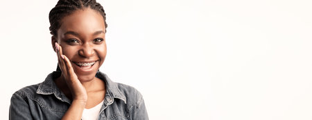 Young woman smiles brightly while showing off her braces in a studio settingの写真素材