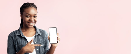 Young woman happily showing her smartphone against a pink backgroundの写真素材