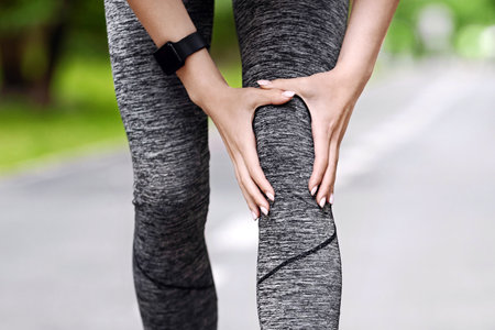 Knee Trauma. Unrecognizable Woman Jogger Hut Her Leg During Running Outdoors