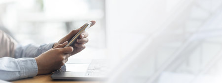 Woman hands holding smartphone and using laptop