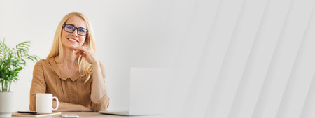 Professional Woman Working at Home, Smiling While Sitting at a Tidy Desk With Laptopの写真素材