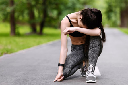 Exhausted Asian Jogger Girl Resting On Path In Park After Long Runの写真素材