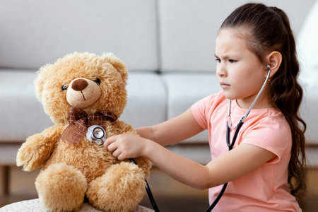 Asian Girl Playing Doctor Treating Teddy Bear Toy At Homeの写真素材