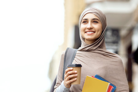 Female student in headscarf having morning coffee before universityの写真素材