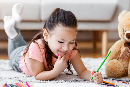 Asian Kid Girl Drawing Lying On Floor At Homeの写真素材