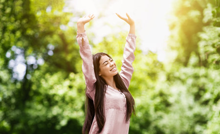 Freedom. Happy asian girl relaxing and enjoying sunny day in city parkの写真素材