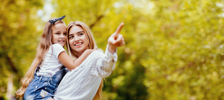 Happy Mom Showing Daughter Something Pointing Finger Standing In Parkの写真素材