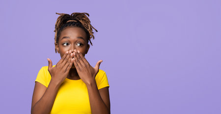 Happy emotional black woman covering her mouth with both palmsの写真素材