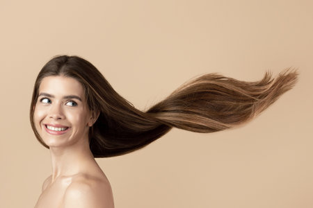 Sensual girl with long shiny hair on beige background, copy spaceの写真素材
