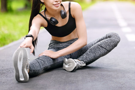 Young asian girl stretching legs before jogging outdoors, warming up for workout