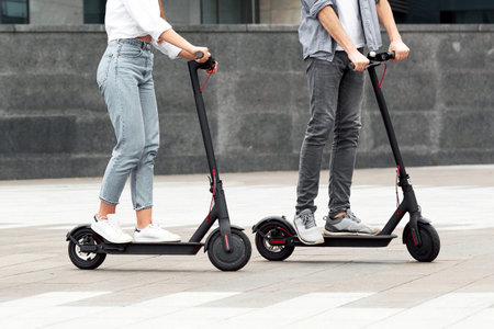 Five friends having pleasant ride on motorized kick scootersの写真素材