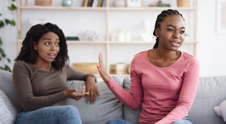Annoyed woman showing stop gesture to her scolding girlfriendの写真素材