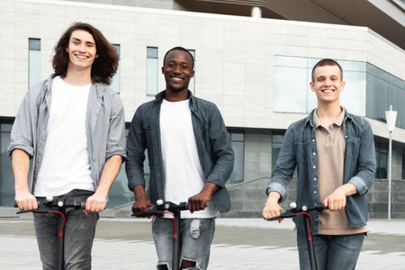 Happy friends having nice ride on motorized kick scootersの写真素材