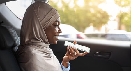 Black Muslim Woman Sending Voice Message And Using Laptop In Car