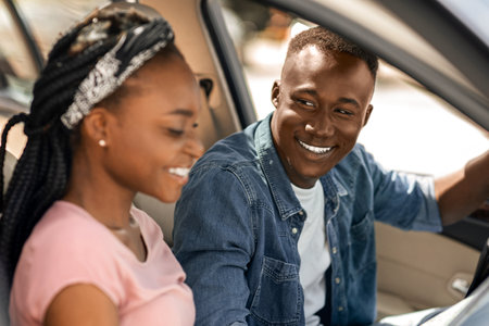 Excited afro american couple travellers looking at map while driving