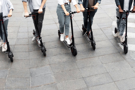Five friends having a nice ride on electric kick scootersの写真素材