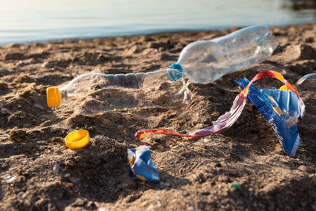 Polluted Beach With Plastic Garbage Lying On Sand Near Waterの写真素材