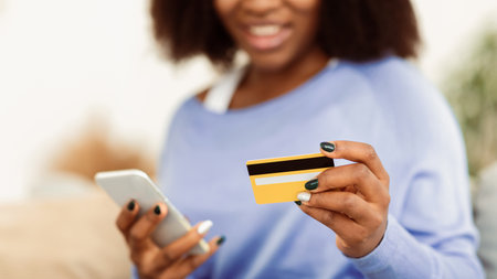 Black woman using phone and credit card at homeの写真素材