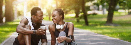 Cheerful Black Athlete Couple Relaxing On Path In Park After Training Outdoors