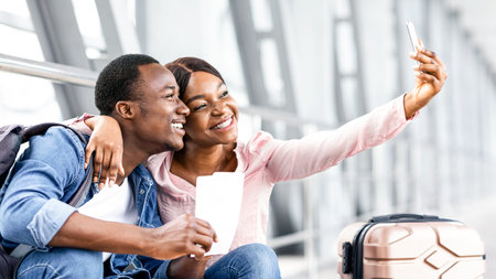 Travel Memories. Cheerful Black Couple Taking Selfie On Smartphone In Airportの写真素材