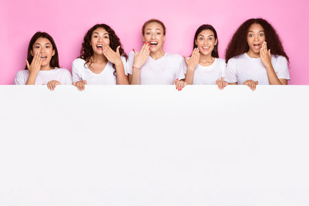 Excited Multiethnic Ladies Holding Poster With Copy Space, Pink Backgroundの写真素材