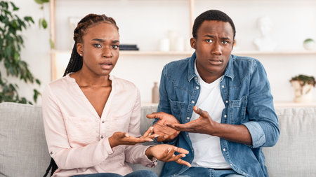 Frustrated Black Couple Sitting On Couch At Therapy Session, Looking With Misunderstandingの写真素材