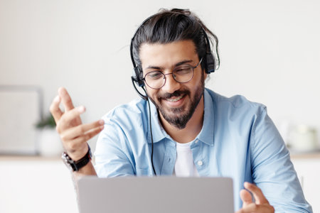 Web Conference. Positive Eastern Guy In Headset Making Video Call Via Laptopの写真素材