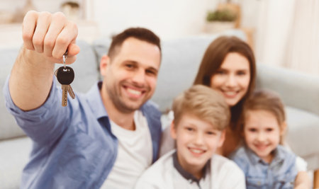 Joyful Family Showing New House Key Sitting Indoors, Shallow Depthの写真素材