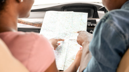 Black couple travellers looking at map while driving, back view