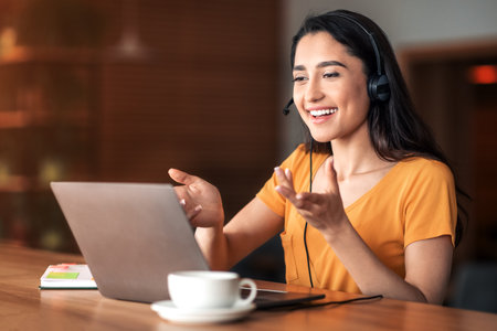Young arab woman having business conference online, cafe interior