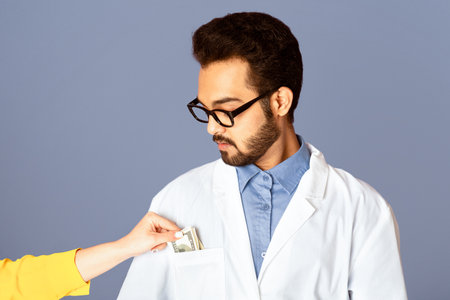 Patient putting money into doctors pocket on lilac backgroundの写真素材