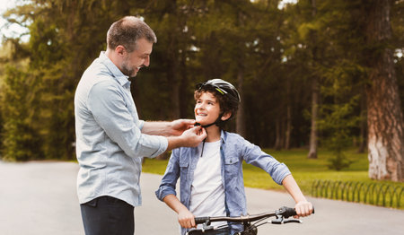 Man putting protective helmet on curly boyの写真素材