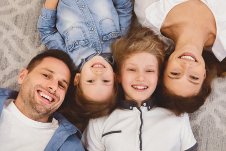 Smiling Parents And Children Lying On Floor Posing Indoors, Above-Viewの写真素材