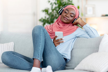 Playlist For Relax. Black Islamic Woman Listening Music On Smartphone At Home