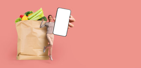 Customer showcasing grocery purchase with a smartphone in hand at homeの写真素材