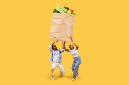 Couple joyfully carrying large paper grocery bag filled with fresh produceの写真素材
