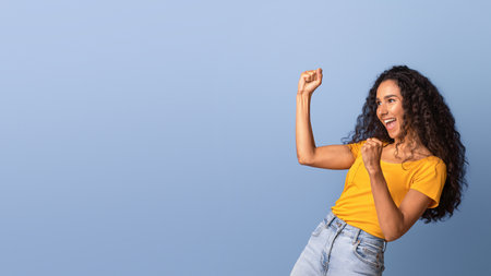 Euphoric brunette woman emotionally celebrating success, raising fists and exclaiming with excitementの写真素材
