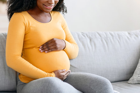Happy african lady expecting child, spending time at homeの写真素材