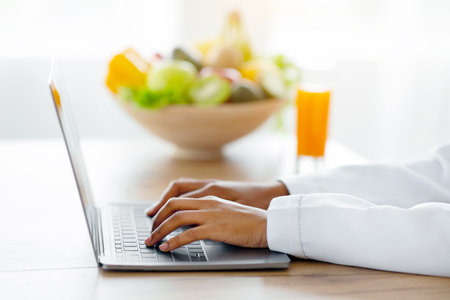 Cropped view of black female dietitian with laptop consulting patient online at clinic, free spaceの写真素材