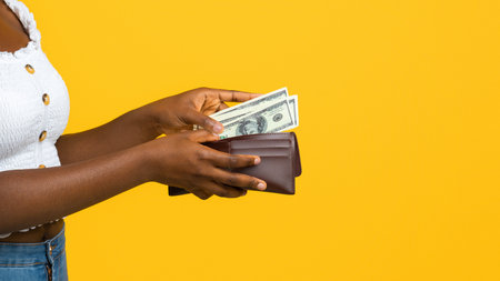 Finance, investment and money saving. Happy black woman putting banknotes into walletの写真素材